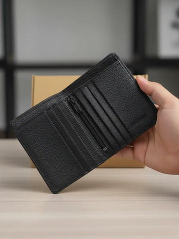 Black leather wallet held by a hand on a neutral background