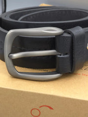 Black leather belt with silver buckle on a cardboard surface