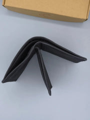 Black wallet on a light gray surface with a brown box in the background