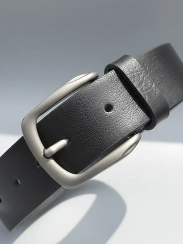 Black leather belt with a silver buckle on a light gray background
