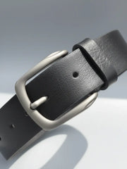 Black leather belt with a silver buckle on a light gray background