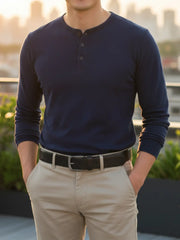 Person wearing a navy long-sleeve henley shirt and beige pants with a blurred outdoor background