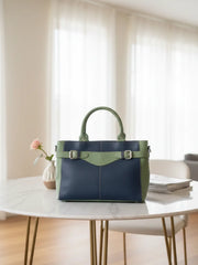 Green and navy handbag on a marble table with a soft focus background