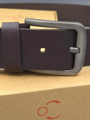Dark brown leather belt with a silver buckle on a cardboard surface