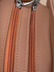 Close-up of a brown leather bag with an orange zipper and silver clasp.