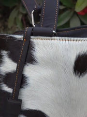 Close-up of a bag with black and white fur texture and leather strap.