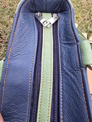 Close-up of a blue leather bag with a zipper, showing texture and stitching details.