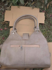 Beige handbag on a cardboard box with grass in the background