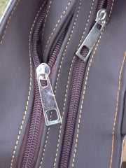 Close-up of a zipper on a brown leather surface with visible stitching.
