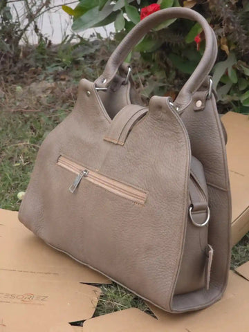 Beige handbag on a cardboard surface with a blurred natural background