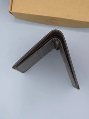 Brown wallet on a white surface with a cardboard box in the background