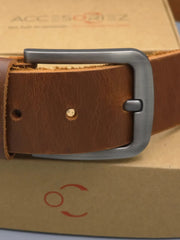 Brown leather belt with a silver buckle on a cardboard box background