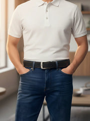 Person wearing a white polo shirt and blue jeans with a blurred indoor background