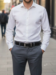 Man wearing a white dress shirt and gray pants on a city street.