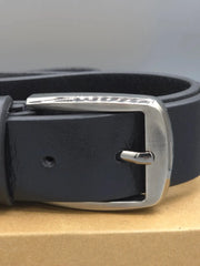 Black leather belt with silver buckle on a cardboard surface