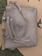 Gray handbag with a tassel on a cardboard box