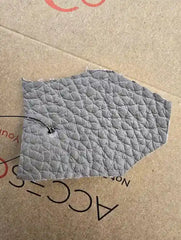 Quilted gray fabric patch on cardboard with visible text