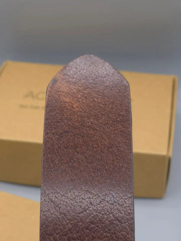 Brown leather belt with a textured finish on a gray background