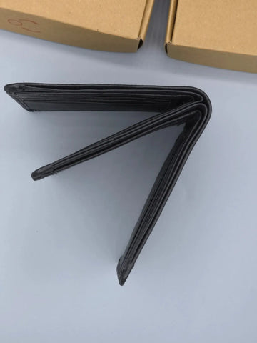 Black wallet on a white surface with cardboard boxes in the background