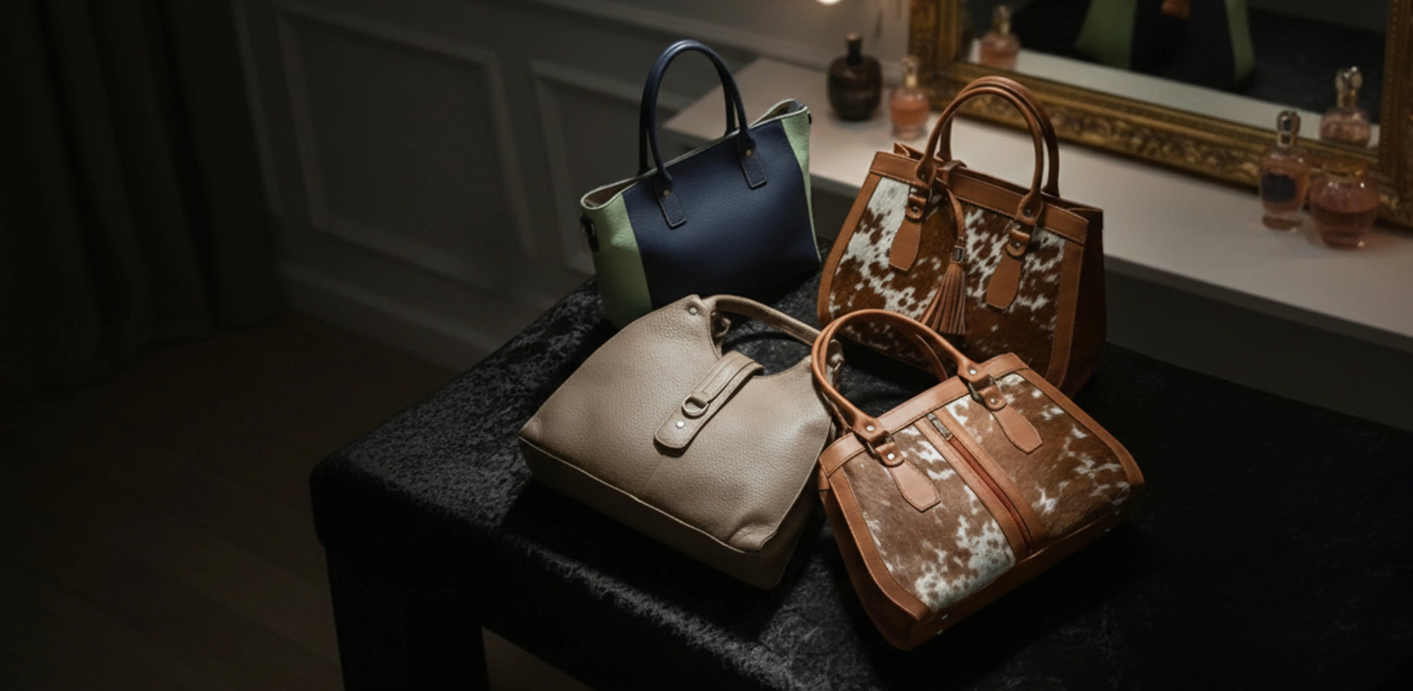 Four handbags on a dark surface with a mirror and decorative items in the background